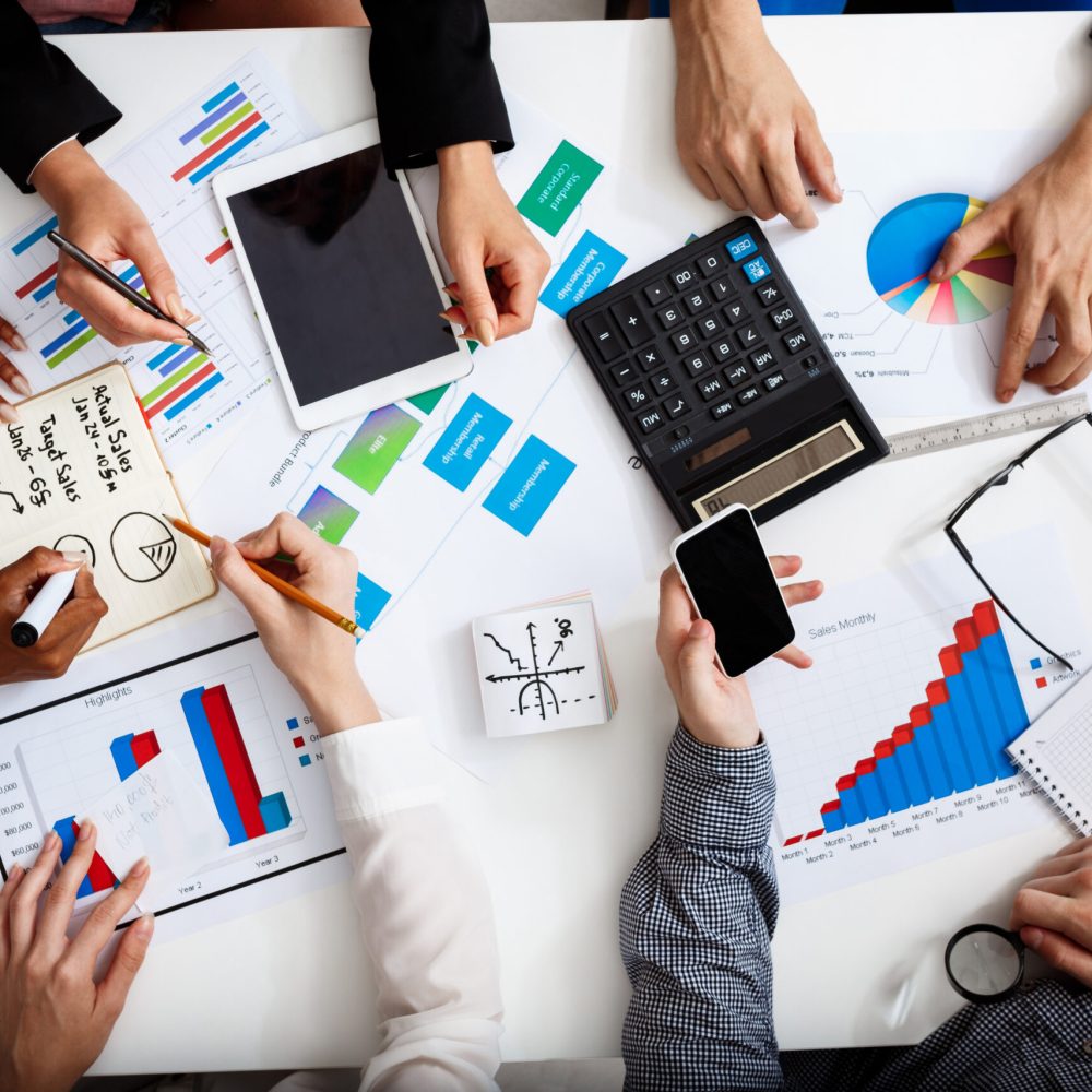 Picture of businessmen's hands on white table with documents, coffee and drafts